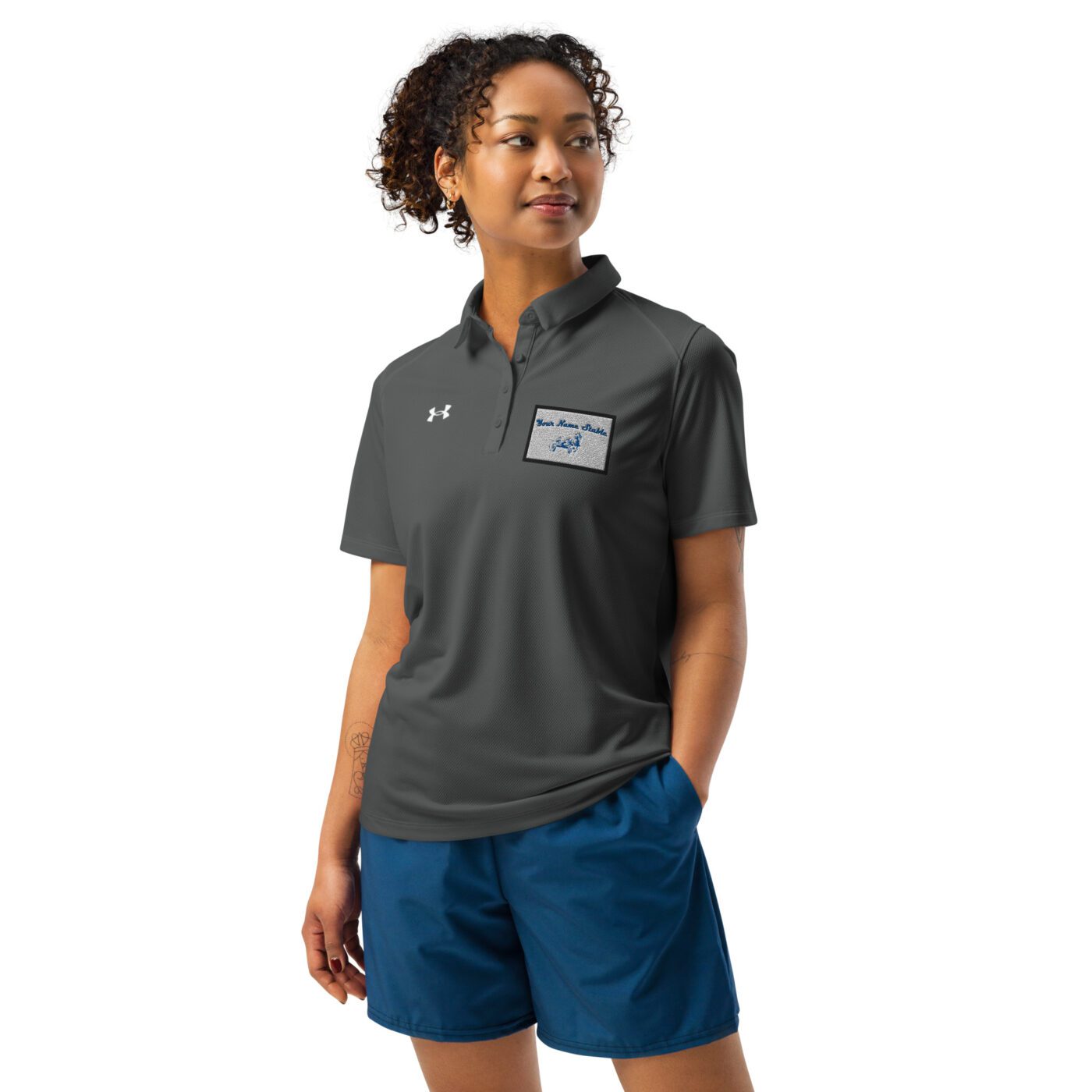 A woman wearing blue shorts and a gray polo shirt.